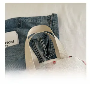 Detail of soft corduroy tote bag with strawberry print and sturdy beige webbing handle