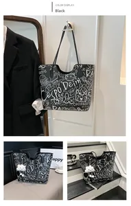 Dettaglio della borsa tote nera con stampe graffiti bianche e ciondolo a nuvola soffice