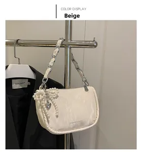 Détail du sac beige en similicuir avec nœud en perles et bandoulière en chaîne