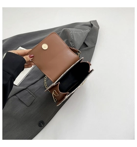 Détail du sac à bandoulière marron avec côté tissé tricolore et chaîne dorée