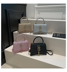 Detailed close-up of textured glitter handbags with metal tassels and letter logo