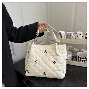 Detailed view of quilted tote bag with black floral embroidery and silver chain strap