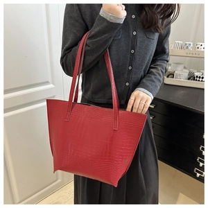 Detail of red crocodile pattern tote bag shown with shoulder strap on a model