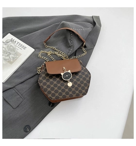 Détail du sac bandoulière hexagonal avec pendentif chat et chaîne dorée sur tissu