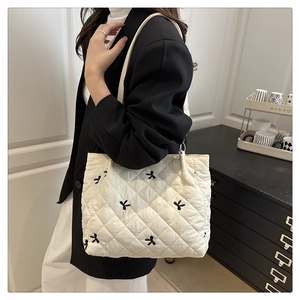 Detail of quilted tote bag with black bow embroidery and classic diamond stitching pattern