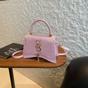 Chic pink structured handbag with glitter texture and gold logo on wooden table