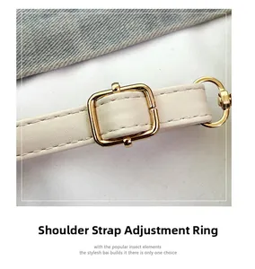 Close-up of white leather shoulder strap with polished gold metal buckle and D-ring