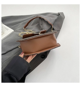 Détail d'un sac bandoulière en cuir marron avec chaîne et boucle en forme de chat