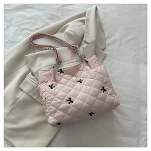 Close-up of pink quilted tote bag featuring black embroidered bows and silver chain strap