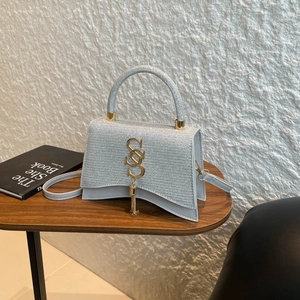 Silver metallic crossbody bag with unique curved base and gold S-shaped tassel charm
