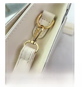 Detailed macro view of high-quality golden metal hook and D-ring on the white handbag