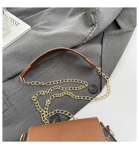 Vue de dessus d'un sac chaîne en cuir marron chic avec motif monogramme sur veste grise