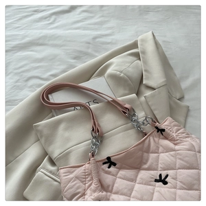 Close-up of pink quilted tote bag with black bow embroidery and silver chain strap