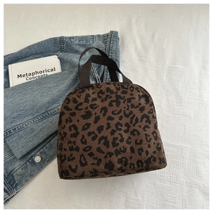 Detail of leopard print corduroy handbag featuring vertical texture and brown canvas handles