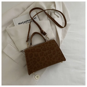 Top view of brown leopard print handbag with gold hardware on white fabric