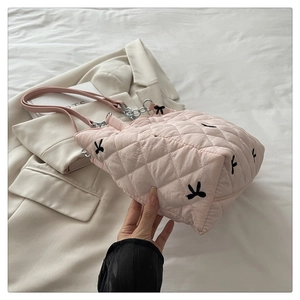 Close-up of pink quilted tote bag with black bow embroidery and metal chain strap