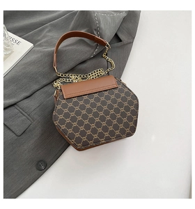 Détail d'un sac hexagonal marron à monogramme avec chaîne dorée et poignée en cuir