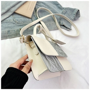 Detail of crossbody bag with silver crinkle texture and beige panel on white background