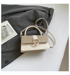 Detail of cream leather handbag with gold glitter flap and D-ring buckle on gray blazer