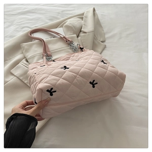 Close-up of quilted pink tote bag featuring black rabbit embroidery and chain strap detail