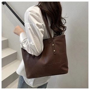 Detail of a dark brown tote bag with crocodile texture leather and gold rivets for work