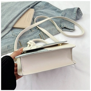 Detail shot of a white crossbody bag with metal accents on a stylish lifestyle background