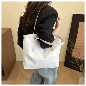 Detail view of white tote bag with faux crocodile texture and slim shoulder straps