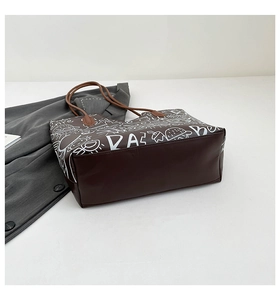 Dettaglio della grande borsa tote marrone con stampa graffiti bianca e base in ecopelle