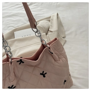 Pink quilted tote bag with black bow embroidery and silver chain strap detail