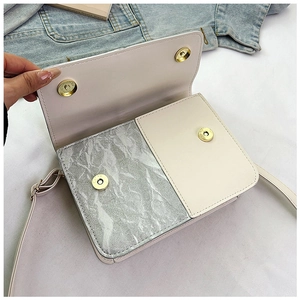 Macro view of contrast color shoulder bag with silver pleats and magnetic closure