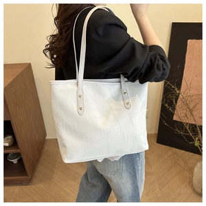 Detailed shot of white tote bag with crocodile texture and gold rivets on shoulder strap