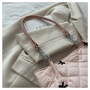Detail of pink quilted tote bag with silver chain strap and embroidered accents