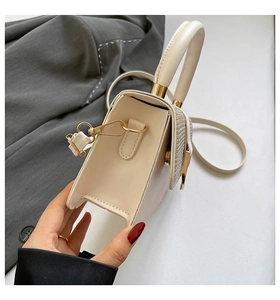 Detail of off-white crossbody bag featuring woven texture flap and gold hardware accents