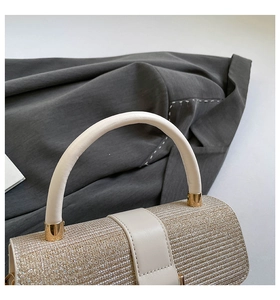 Detailed macro view of golden glitter texture and cream leather handle on elegant handbag