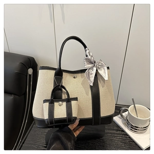 Detail of canvas tote bag with black leather trim, silk scarf, and mini coin pouch accessory