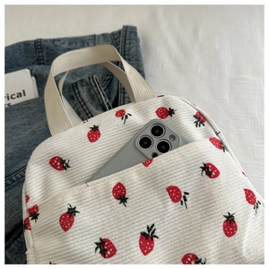 Detail of strawberry corduroy lunch bag with front pocket holding a smartphone