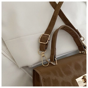Details einer braunen Vintage-Handtasche mit goldenem Drehverschluss und Beschlägen