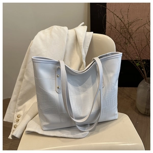 Detail view of white crocodile pattern tote bag with leather texture and rivet accents
