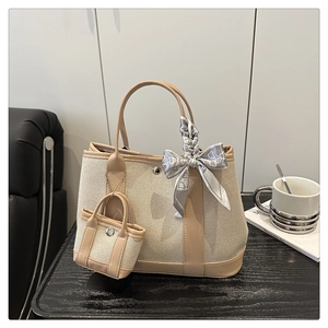 Detail of canvas tote bag with leather trim, mini charm and decorative silk scarf