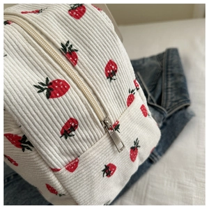 Close-up of strawberry print on white corduroy bag with durable silver metal zipper detail
