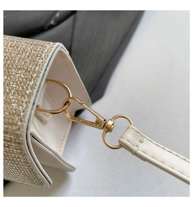 Close-up of golden glitter handbag with metal hook hardware and neat stitching detail