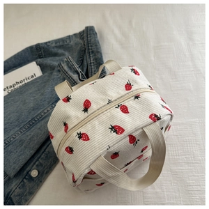 Detailed close-up of corduroy lunch bag with red strawberry prints and beige handles