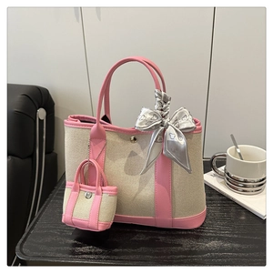 Close-up of canvas tote bag with pink leather trim and decorative silk scarf detail