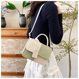 Detail of a two-tone crossbody square bag in cream and green with a fashion tag