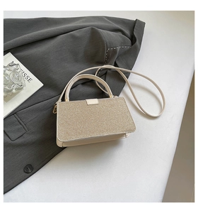 Detail of champagne gold sequin texture and cream leather handle on elegant crossbody bag