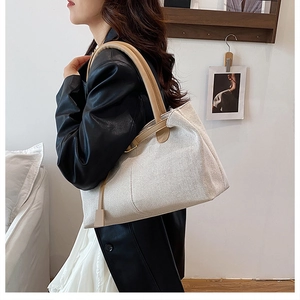 Detail view of beige woven tote bag with brown leather handles for commuting