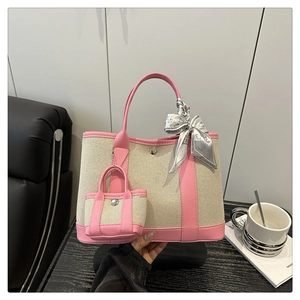 Detailed view of canvas tote bag featuring pink leather trim and decorative silk scarf
