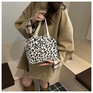 Detail of leopard print corduroy tote bag featuring a front pocket and cream handles