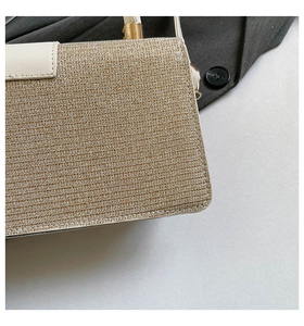 Detailed shot of gold woven fabric with cream leather stitching and pale gold hardware