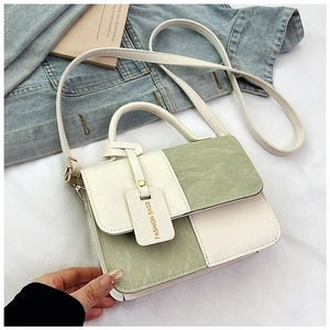 Detail of color block handbag with wrinkled green texture and detachable crossbody strap